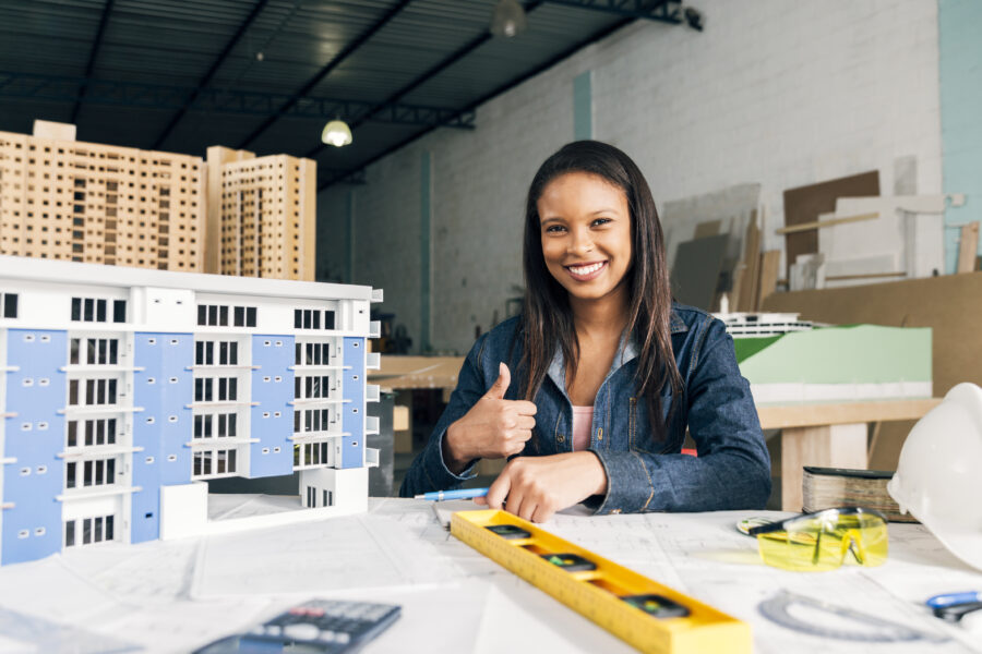 smiling-african-american-woman-showing-thumb-up-near-model-building